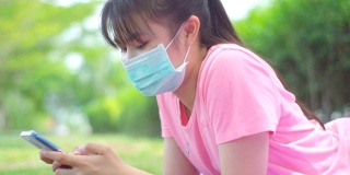 新常态，少女在新冠肺炎疫情下戴口罩使用手机