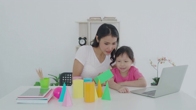 亚洲女学生与母亲视频会议电子学习与教师计算机学习几何形状在家教学。在家教育和远程学习，在线，教育和互联网。