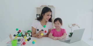 亚洲女学生与母亲进行视频会议，与教师进行电子学习，探讨在家中进行科学教学的电脑学习。在家教育和远程学习，在线，教育和互联网。
