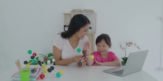 亚洲女学生与母亲进行视频会议，与教师进行电子学习，探讨在家中进行科学教学的电脑学习。在家教育和远程学习，在线，教育和互联网。