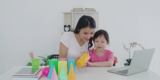 亚洲女学生与母亲视频会议电子学习与教师计算机学习几何形状在家教学。在家教育和远程学习，在线，教育和互联网。