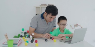亚洲男孩学生与父亲视频会议电子学习与教师电脑学习在家里的科学教学。在家教育和远程学习，在线，教育和互联网。
