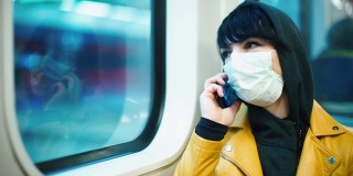 一位戴着医用口罩的女志愿者正在地铁里打电话。