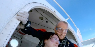 教练和一名女子正带着降落伞跳出飞机。
