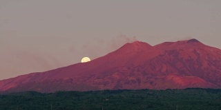 黎明时分，意大利西西里岛的埃特纳火山喷发，背景是超级月亮