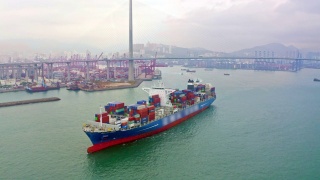 集装箱货轮从码头的商业港口或集装箱仓库与香港城市景观的商业物流，进出口，航运或运输。视频素材模板下载
