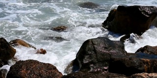 在加州旧金山的海洋海滩，海浪拍打着悬崖岩石的风景。泡沫的水，明亮的阳光