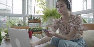 新冠肺炎疫情发生后，年轻的亚洲女性在被隔离期间在家客厅网购，在温室的小花园中放松，在室内花园的概念