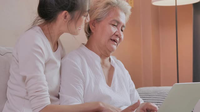 祖母64岁的亚洲年轻女性，在社交距离期间使用家里的笔记本电脑网购，以预防冠状病毒或新冠病毒的流行。网上购物的概念。