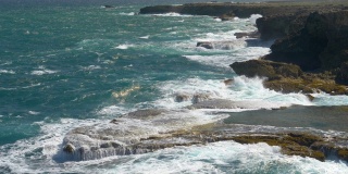慢镜头:巨浪冲击着岩石峭壁，溅起狂乱的水花