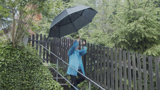 小男孩带着大雨伞在雨中行走