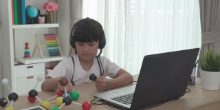 亚洲女学生视频会议电子学习科学课与老师和同学在家里的客厅电脑上。在家教育和远程学习，在线，教育和互联网。