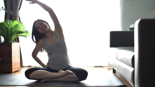 怀孕的亚洲母亲在客厅练瑜伽