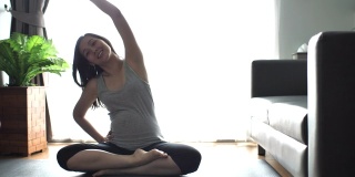 怀孕的亚洲母亲在客厅练瑜伽