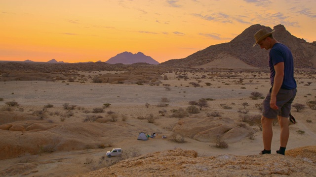 非洲纳米比亚，男摄影师拿着相机看着风景优美的斯匹茨科佩山峰