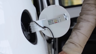 环保电动汽车充电镜头关闭妇女的手从电动汽车上拔下充电器后充电。视频素材模板下载