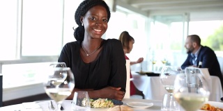 在一家豪华餐厅吃午餐时，女商人对着镜头微笑