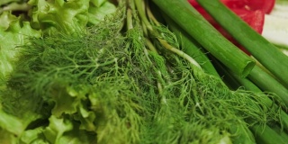 生蔬菜莳萝，沙拉和大葱特写。素食。新鲜的蔬菜在桌上轮转。