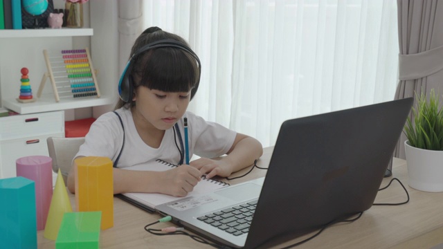 亚洲女学生视频会议e-learning几何形状与老师和同学在家里的客厅电脑上。在家教育和远程学习，在线，教育和互联网。