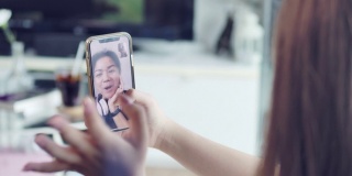 一名亚洲少女在隔离期间用智能手机与朋友视频通话。