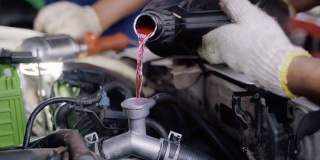 汽车修理工在车库里的散热器中注入冷却液。