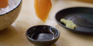 用筷子夹紧手挑三文鱼生鱼片在日本餐馆里蘸着大豆和芥末。
