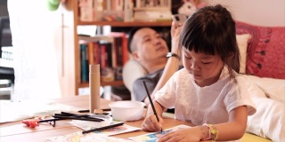 一个亚洲女孩和父亲在家画画