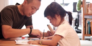 一个亚洲女孩和父亲在家画画