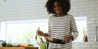 美丽的年轻混血女子微笑着在煎锅上做饭，在锅里翻蔬菜