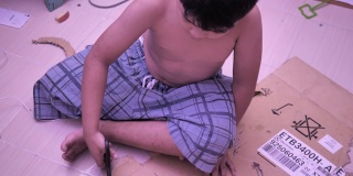 小男孩用剪刀剪纸，在室内做手工