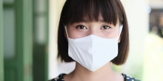 亚洲妇女戴着卫生口罩，美丽的亚洲女孩戴着口罩保护传染性冠状病毒2019冠状病毒，使用智能手机移动上网café放松，保持安全健康