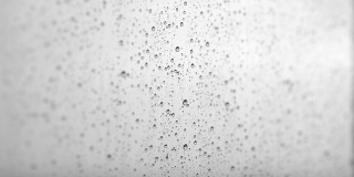 雨滴从窗户上流下的微距摄影。窗外的雨
