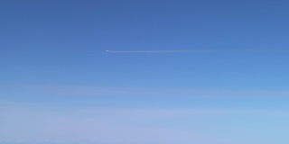 飞行中的飞机留下的白色痕迹。飞机在蓝天白云间飞翔