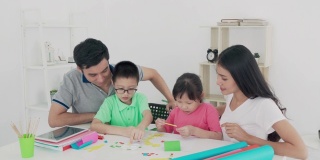 亚洲家庭与父亲，母亲，女儿和儿子编辑彩色纸制作艺术品，并参与手工艺项目和奖励活动在家自学。