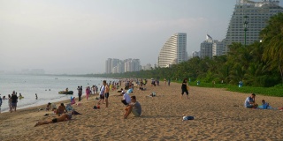 日落时分三亚市拥挤的海滩湾慢镜头全景4k海南中国