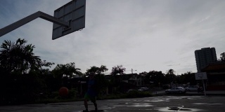 清晨，一名亚裔中国老人在篮球场上练习篮球，慢镜头中的剪影
