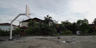 早上，一名亚裔中国男子在篮球场练习篮球比赛