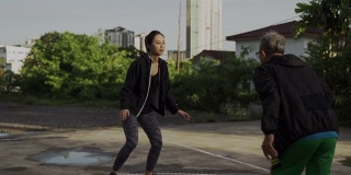 早上，一名亚裔中国老人和他的女儿在篮球场练习篮球