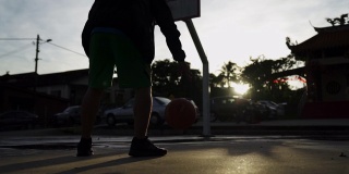 早上，一名亚裔中国男子在篮球场练习篮球比赛