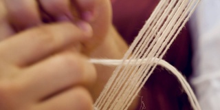 特写妇女的手编织与传统织布机。织机。细部的传统编织手工织机与羊毛近。传统的古老的织机。少数民族服装