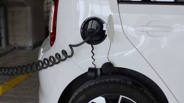 电动汽车或电动汽车在充电站充电。连接充电口的线缆。