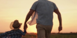 SLO MO父亲和儿子一起在一个田野在日落的质量时间