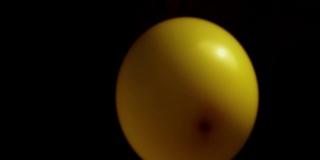 黑色背景中的黄色气球正在膨胀