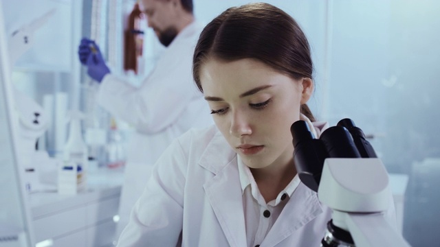 使用显微镜工作的女性亚洲科学家。背景研究伙伴