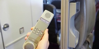女空乘人员在飞行中拿起对讲机并拨打紧急电话。飞机设备。