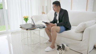亚洲男子，上衣穿西装或职业装，下身穿运动裤或平角裤。商务视频会议使用笔记本电脑和平板电脑进行在线会议。在家工作和远程工作。视频素材模板下载