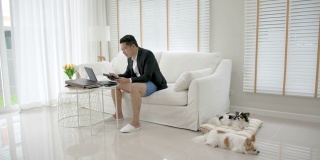亚洲男子，上衣穿西装或职业装，下身穿运动裤或平角裤。商务视频会议使用笔记本电脑和平板电脑进行在线会议。在家工作和远程工作。