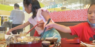 孩子们一起在餐馆吃素琪烧中国菜火锅和蔬菜。