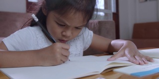 亚洲女孩写和做她的家庭作业的慢动作。居家教育理念。