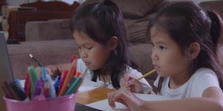 两个亚洲女孩用笔记本一起学习在线技术的慢动作。